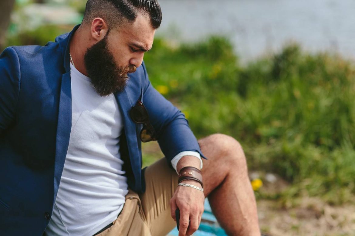 Un homme barbu au style urbain portant une chevalière homme acier discrète à la main.