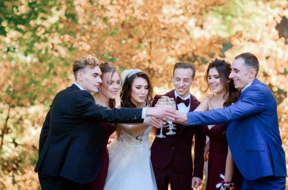 Mariés et invités trinquant avec des coupes de champagne en extérieur pour illustrer comment annoncer un mariage surprise aux proches.